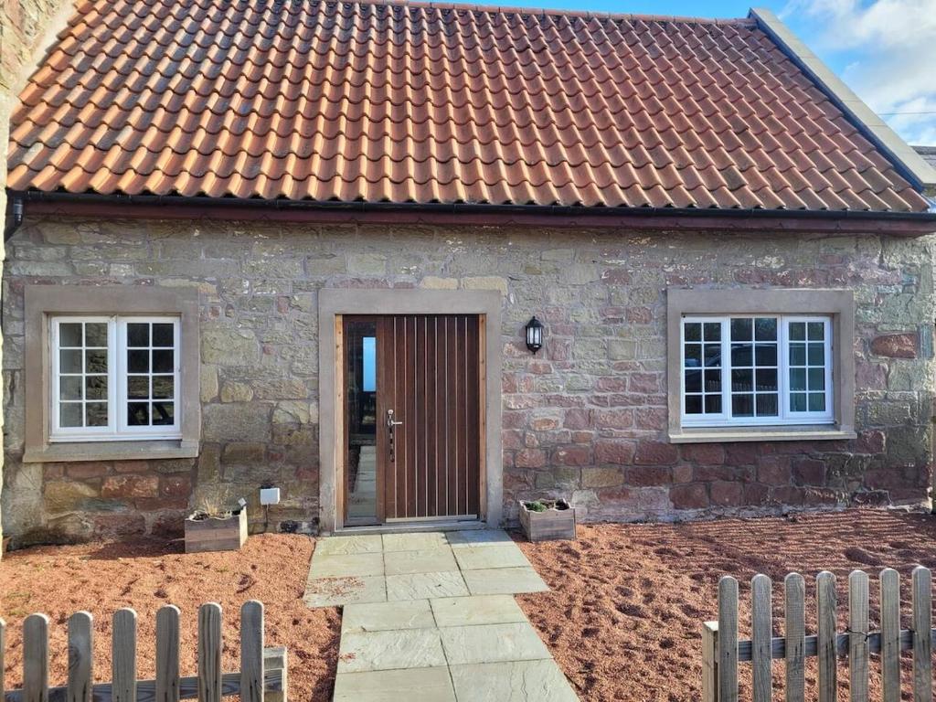 a stone house with a brown door and windows at Cosy country cottage beside Ancient Woodlands in Paxton