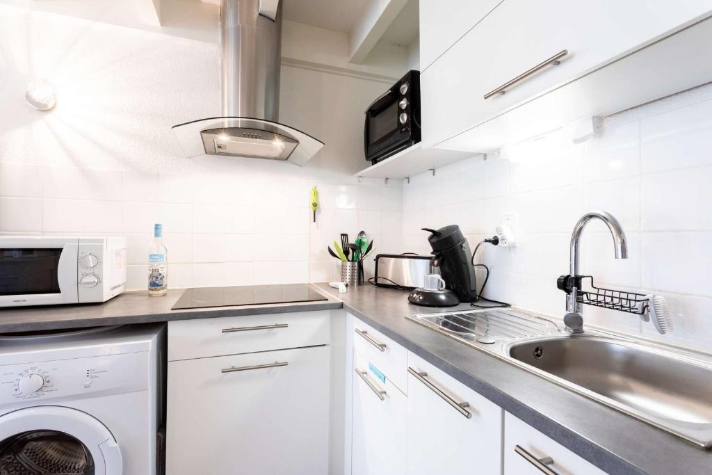 une cuisine blanche avec un évier et un micro-ondes dans l'établissement Maison proche du lac !, à Biscarrosse