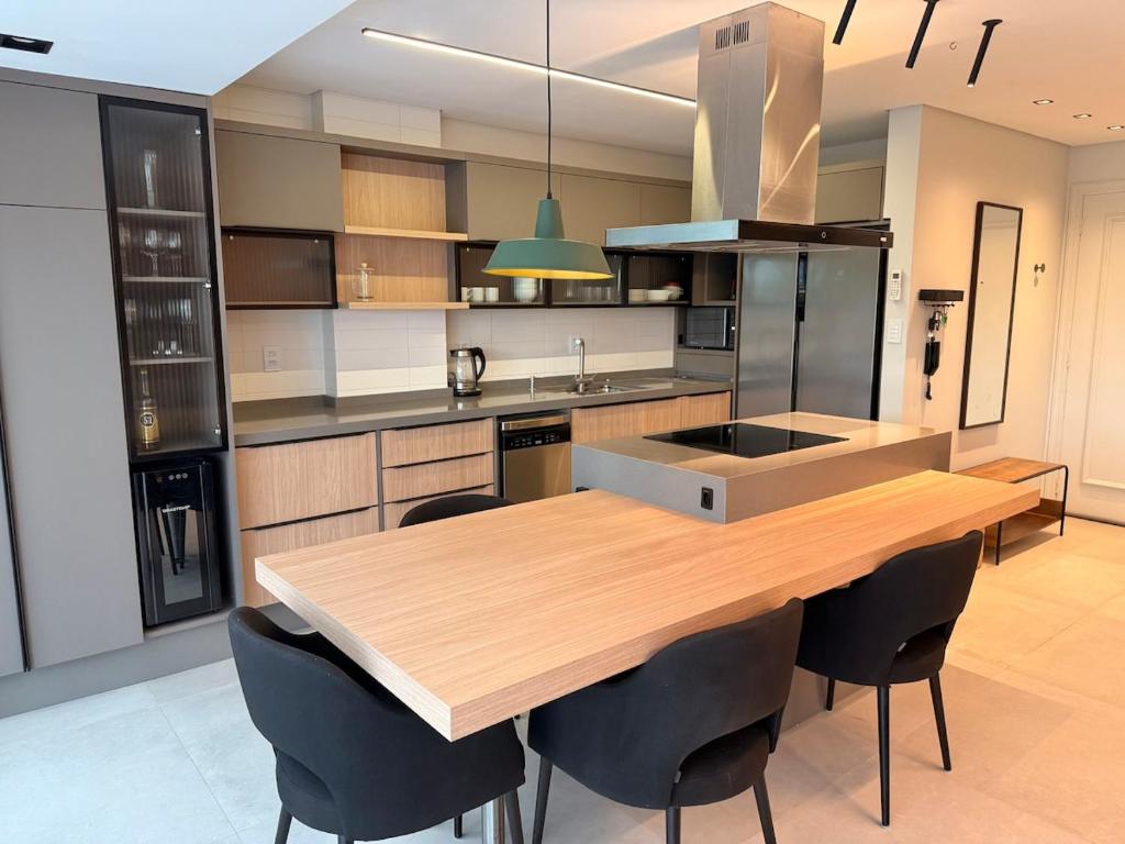 a kitchen with a wooden table and black chairs at Apê Sunshine| Terraço| Interação com animais in Florianópolis