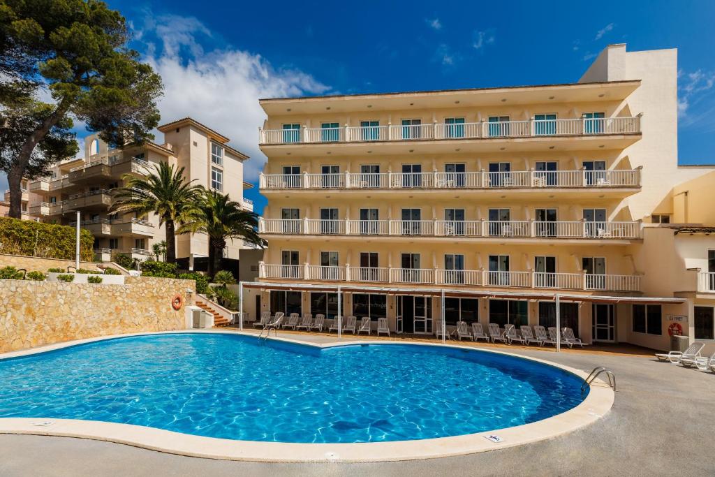 a hotel with a large swimming pool in front of a building at O7 Club Cala Ratjada in Cala Ratjada
