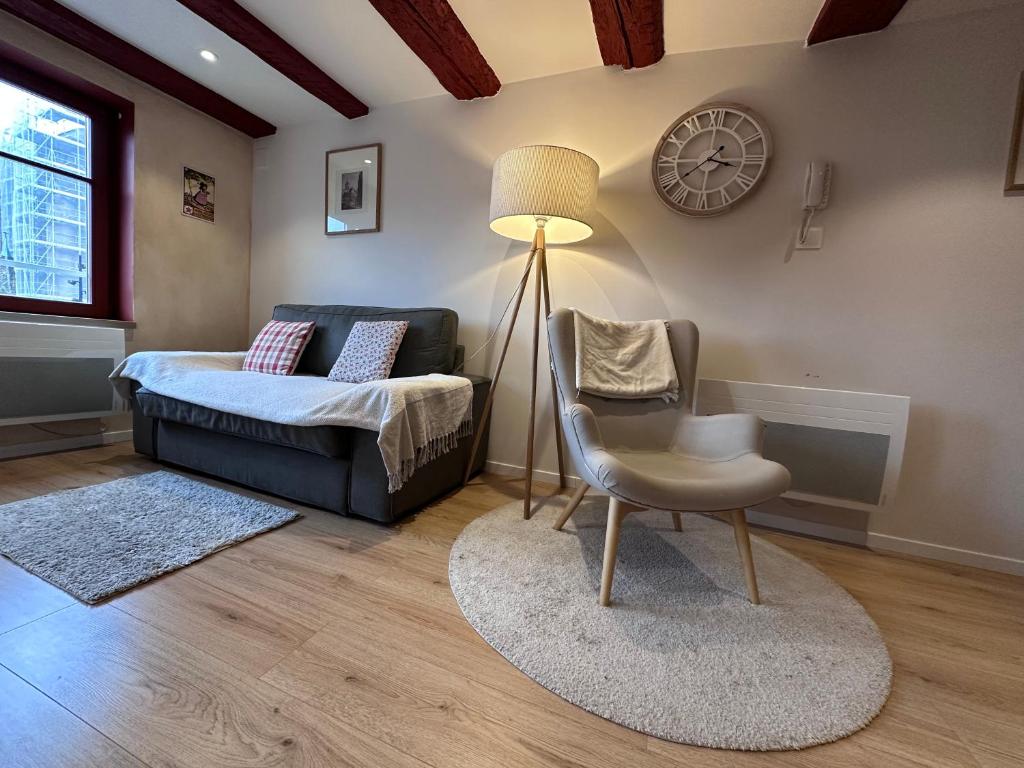 a living room with a couch and a chair and a clock at B'm Yerri - Centre ville - vue Cathédrale in Colmar