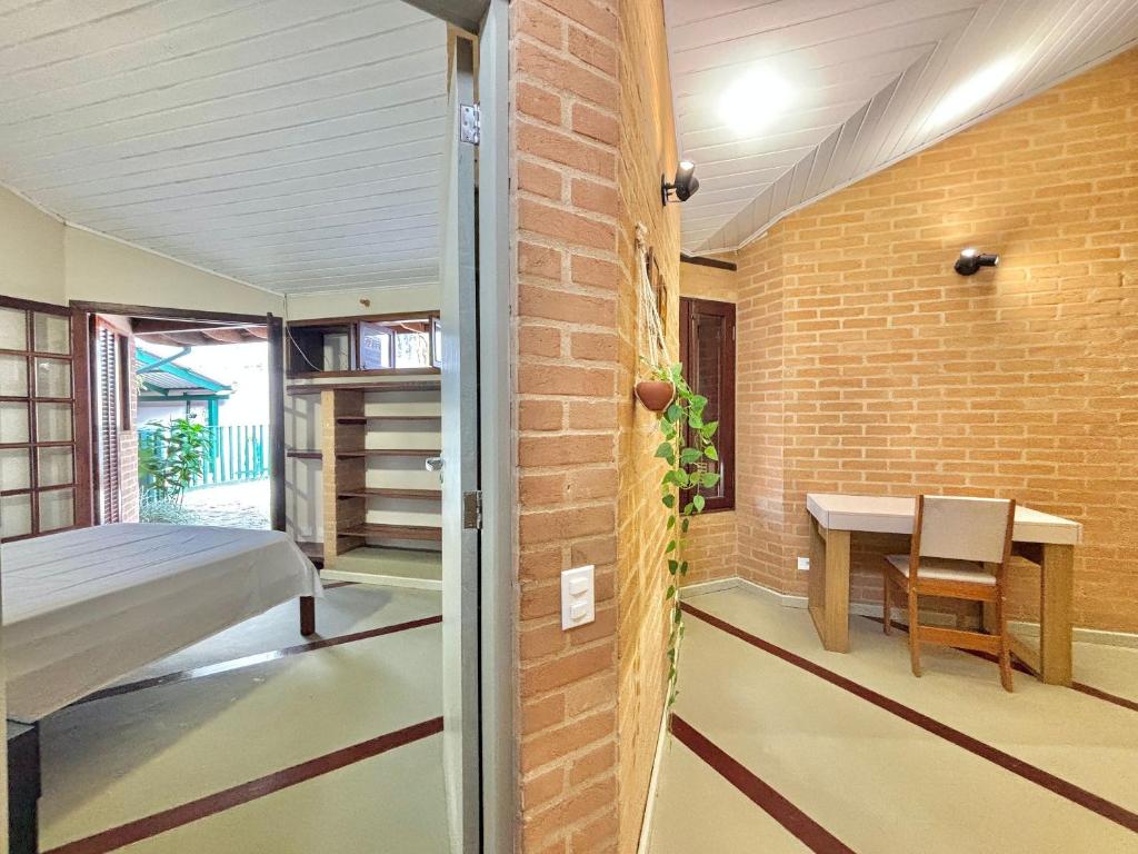 a bedroom with a bed and a desk in a brick wall at Manaca House_ refúgio charmoso_Centro c/ 2 quartos in Ubatuba