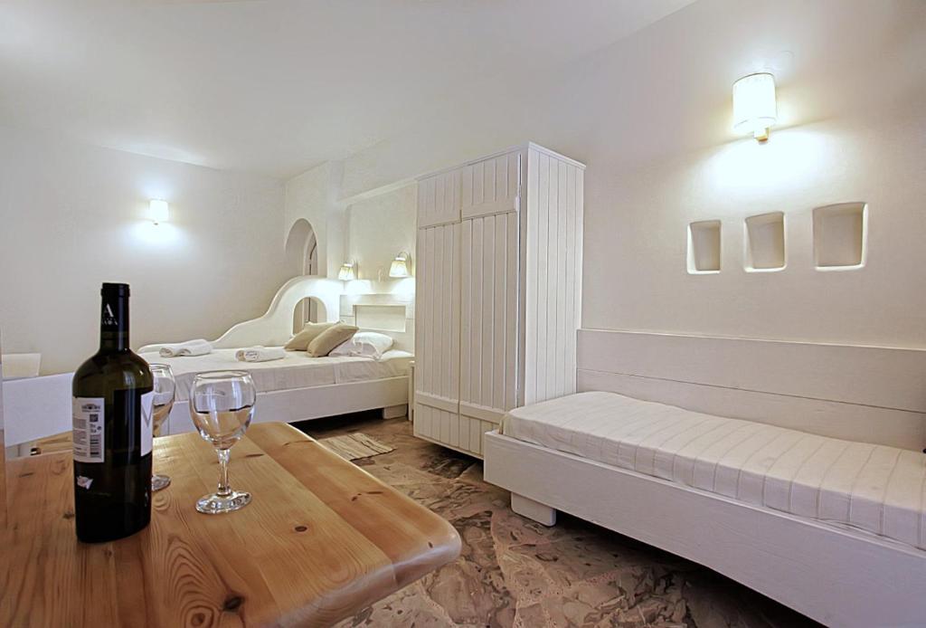 a room with two beds and a bottle of wine on a table at Glaros Studios in Naxos Chora