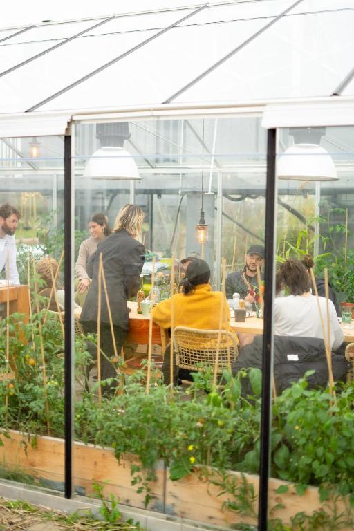 a group of people sitting at a table in a greenhouse at Basecamp Tiny House Eco-resort IJmuiden in IJmuiden