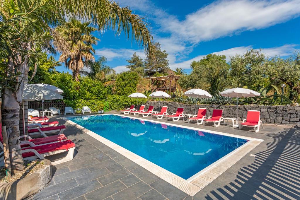 a pool with chairs and umbrellas next to a resort at Etnalandhauser in Piedimonte Etneo