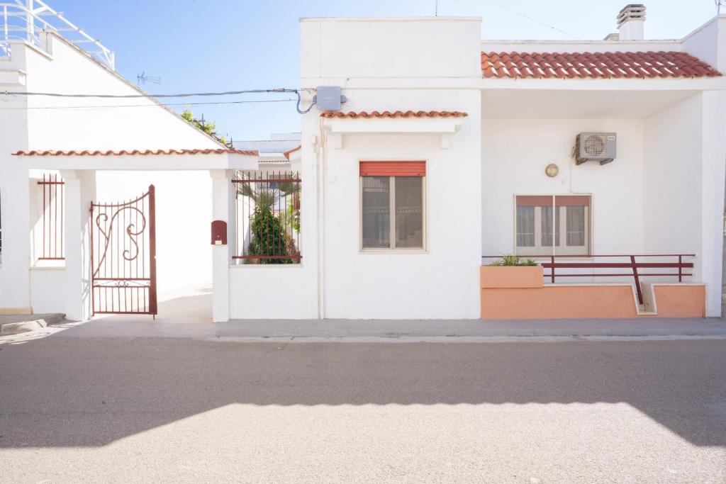a white house with a gate on a street at Villa Camilla by SALENTO OASIS in Porto Cesareo