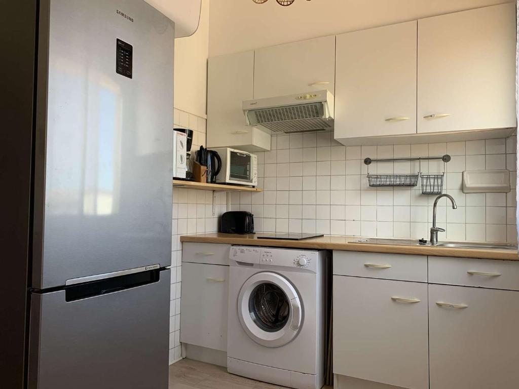 une cuisine blanche avec une machine à laver à l'intérieur dans l'établissement Appartement rénové 4-6 pers à 200m de la plage avec parking privé, centre de Saint Pierre - FR-1-229D-122, à Fleury