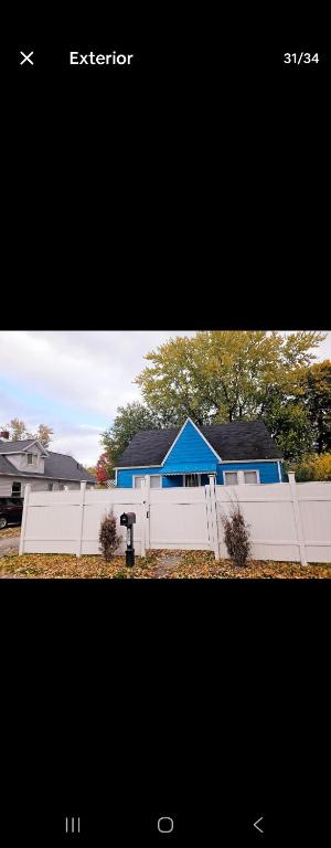 a house with a white fence and a blue roof at Blue Lake in Saginaw