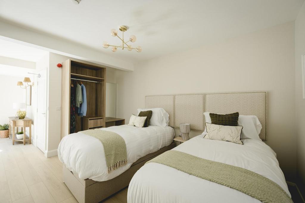 two beds in a room with white walls at The Old Schoolhouse - The Courtyard in Donegal