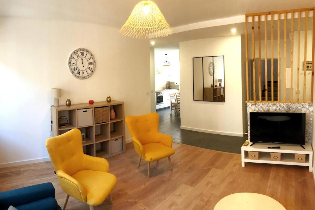 un salon avec deux chaises et une télévision dans l'établissement Appartement 3 chambres - grande terrasse, à Saint-Nazaire