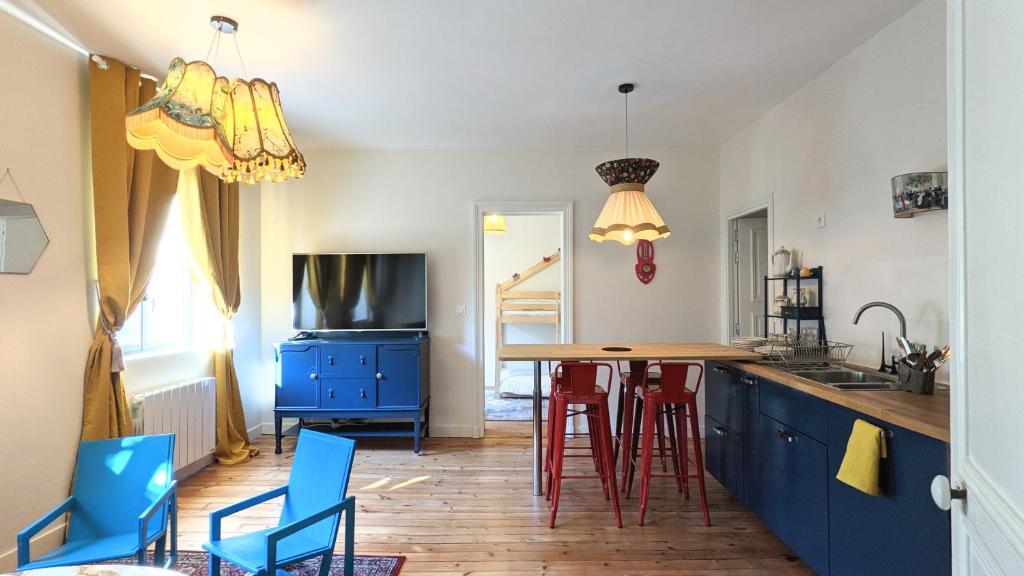 une cuisine avec des placards bleus et une table avec des tabourets dans l'établissement Maison Familiale - Centre Ville - 2 chambres, à Angers