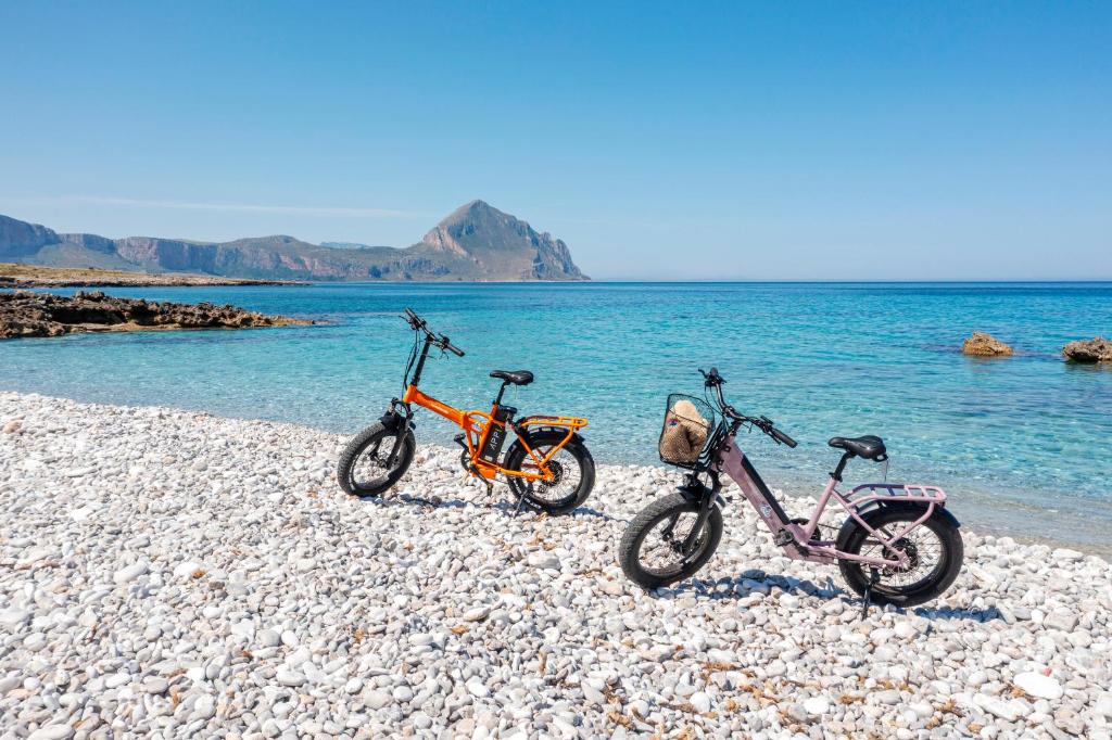 two bikes parked on a rocky beach near the water at Case Vacanza Loria in Castelluzzo