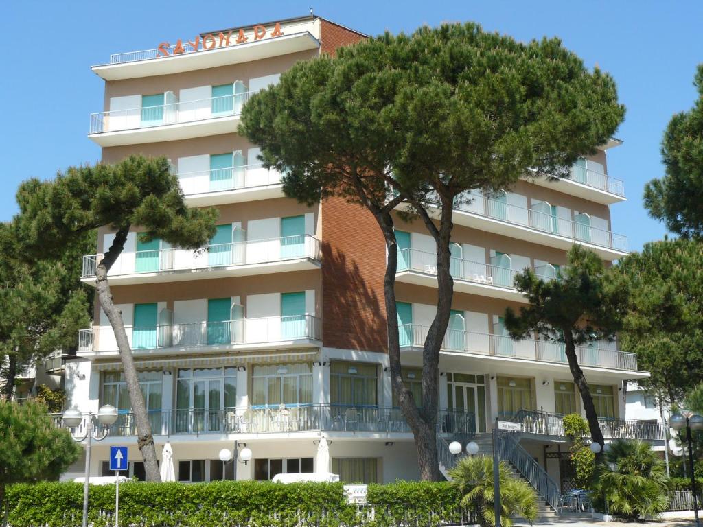 un grand bâtiment blanc avec des arbres devant lui dans l'établissement Hotel Sayonara, à Milano Marittima