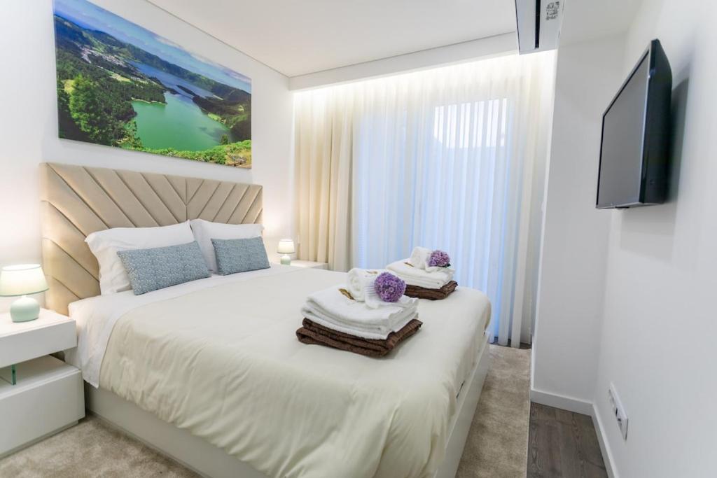 a bedroom with a bed with towels and a tv at GuestReady - Passal Guesthouse in Ponta Delgada