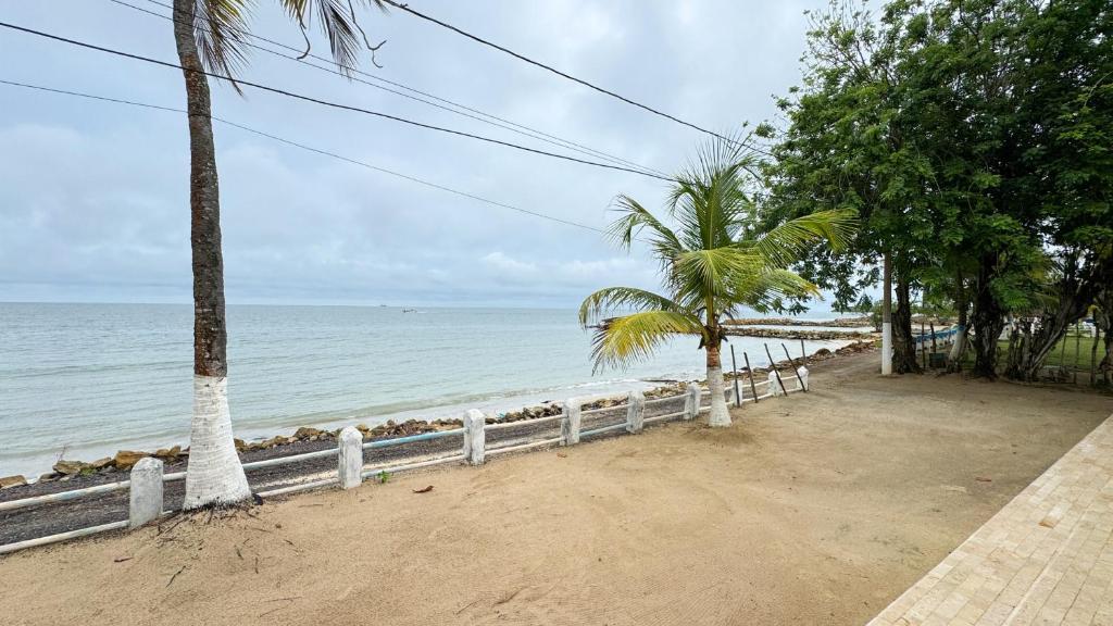 a beach with a fence and trees and the ocean at Cabaña Costa de Oro in San Antero