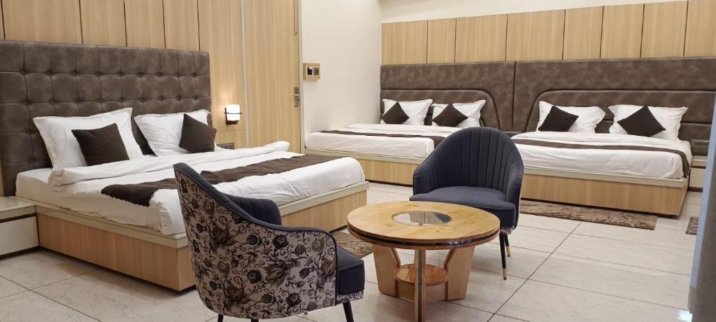 Una habitación de hotel con dos camas y una mesa y sillas. en Hotel Jai Palace, en Ajmer