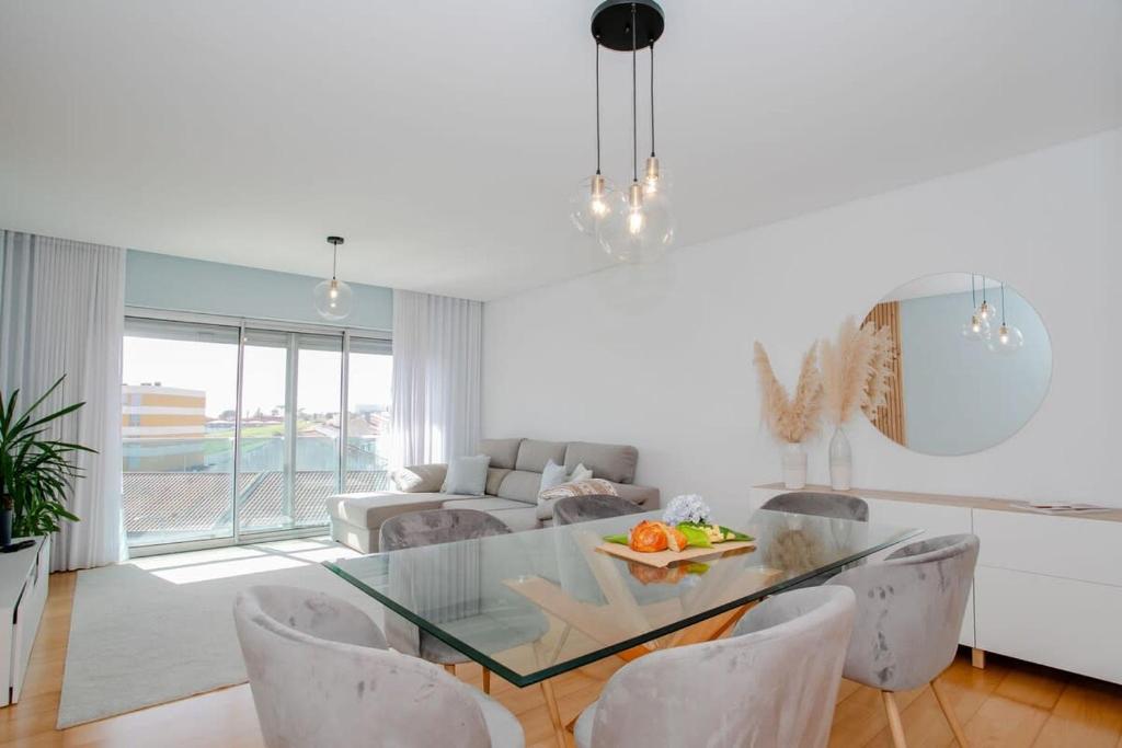 ein Wohnzimmer mit einem Glastisch und weißen Stühlen in der Unterkunft GuestReady - Salomão Luminous Apartment in Senhora da Piedade