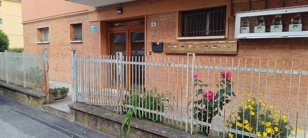 a brick house with a fence and some flowers at Armonia Affittacamere in San Vicenzo di Galliera
