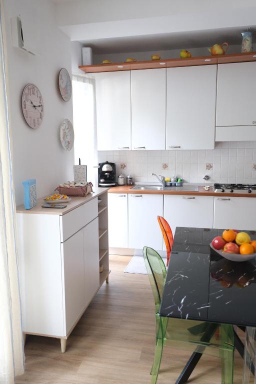 a kitchen with white cabinets and a table with a bowl of fruit at Casa Diana by PortofinoVacanze in Rapallo