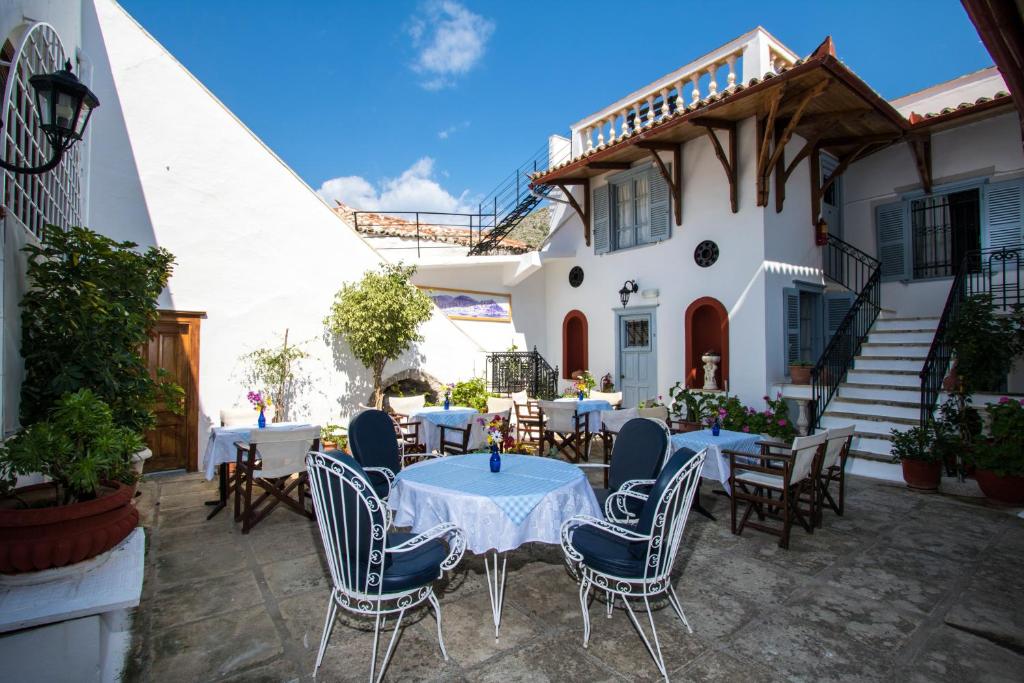 un patio avec des tables et des chaises en face d'un bâtiment dans l'établissement Achilleas Pension, à Hydra