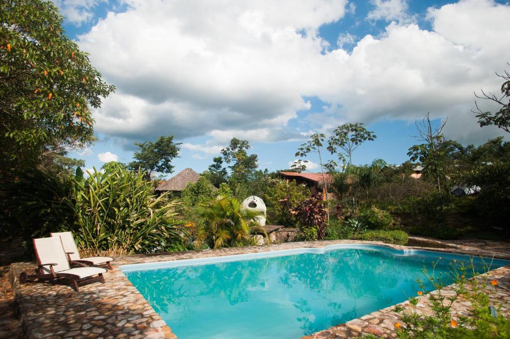 a swimming pool in a garden with a chair next to it at Catavento Pousada in Alto Paraíso de Goiás