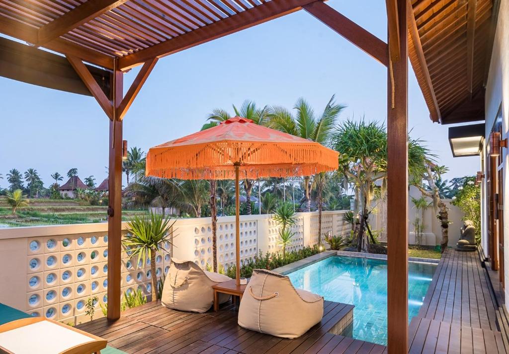 a patio with an umbrella and a swimming pool at Dijero at Umah Bali in Ubud