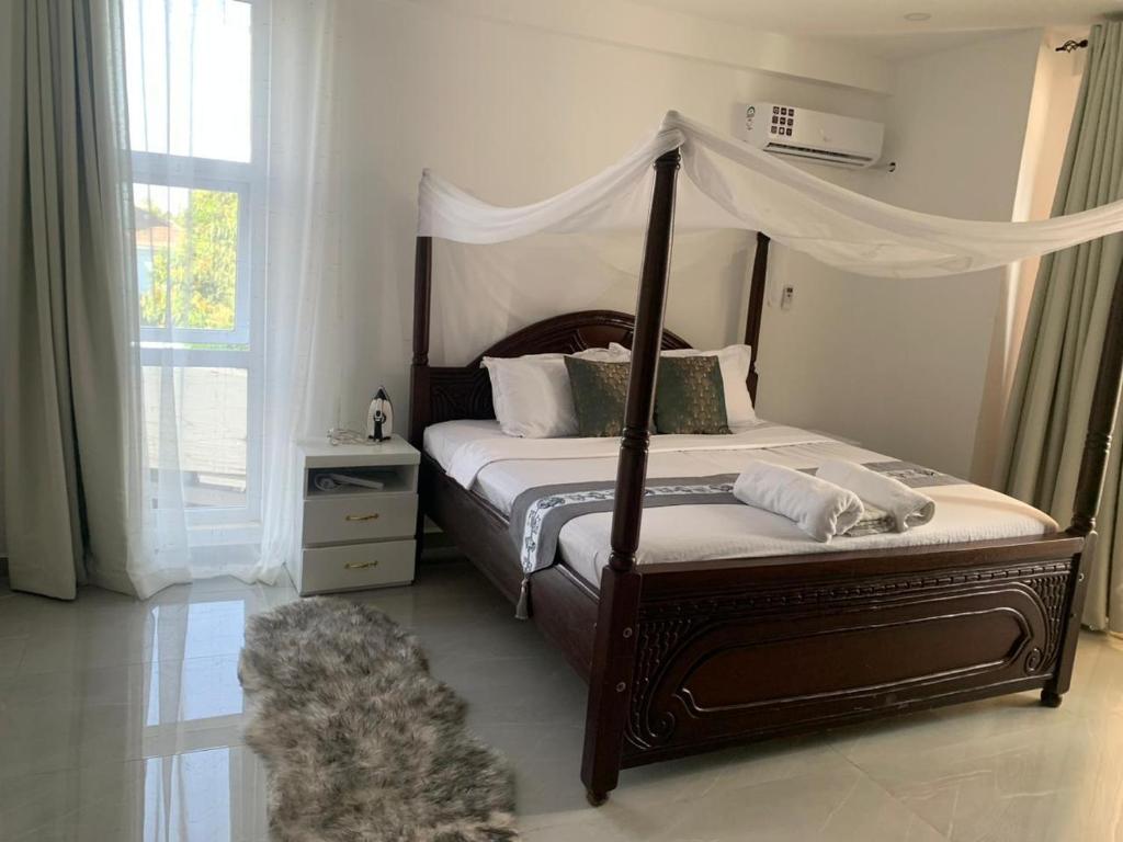 ein Schlafzimmer mit einem Himmelbett und einem Teppich in der Unterkunft Three bedroom in aqua nyali in Mombasa