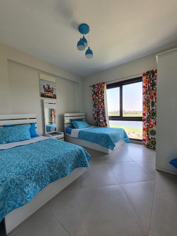 a bedroom with two beds and a large window at Apartment at Marassi in El Alamein