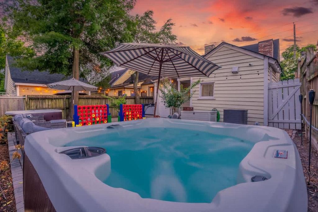 a swimming pool with an umbrella and chairs and a house at Hot Tubs - DT Duplex - Two Blocks off Forsyth Park in Savannah