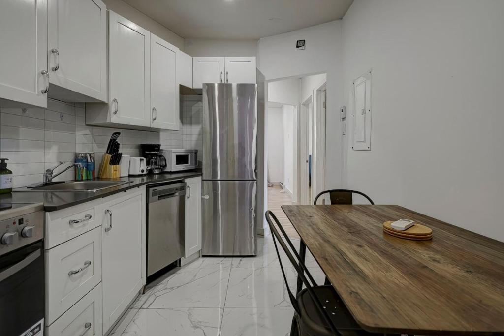 uma cozinha com uma mesa de madeira e uma geladeira em The NDG Nest A Relaxing 3BR Getaway in DT MTL em Montréal