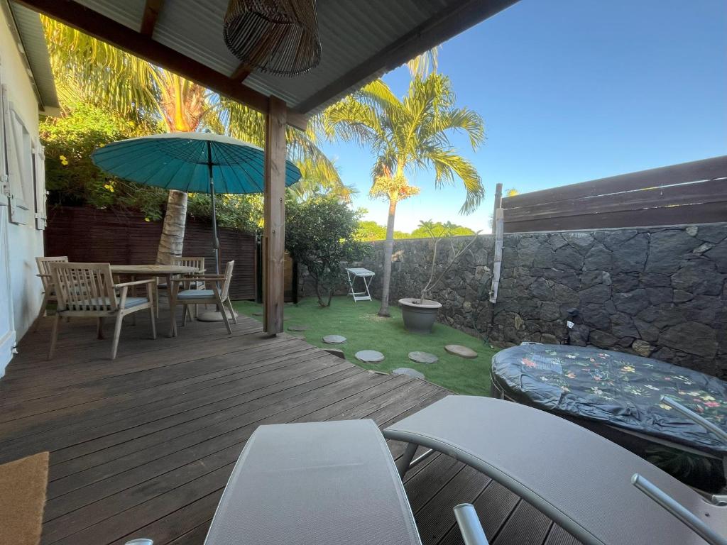 a wooden deck with a table and an umbrella at Ti Kaz avec SPA, proche du lagon in Saint-Gilles les Bains