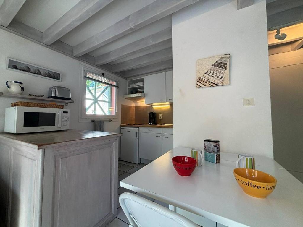 une cuisine avec une table avec des chaises et un micro-ondes dans l'établissement Maison mitoyenne en duplex avec jardin proche lac, à Biscarrosse