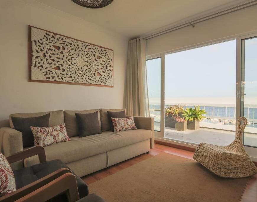 uma sala de estar com um sofá e uma janela grande em GuestReady - Marina view top floor with terrace em Ponta Delgada