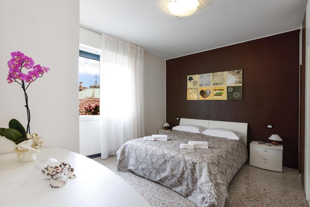 sypialnia z łóżkiem i wazonem z fioletowymi kwiatami w obiekcie Brick House Treviso w mieście Treviso