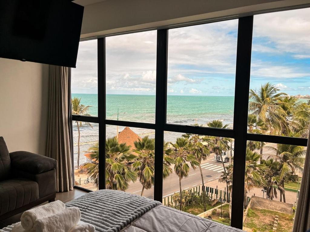a bedroom with a view of the beach and the ocean at Residencial Loft - Studio -407 in Maceió