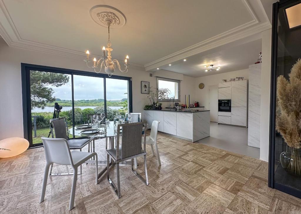 une salle à manger et une cuisine avec une table et des chaises dans l'établissement Maison spacieuse et élégante vue sur l'etang de Lannenec à 600m du Fort-Bloqué, à Ploemeur