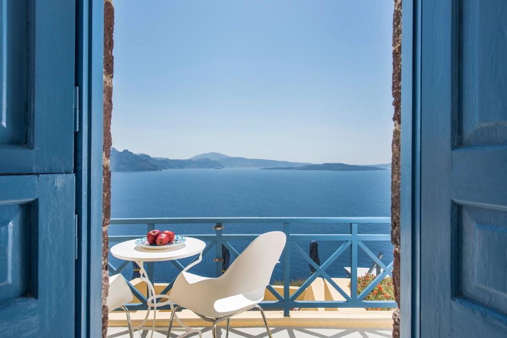 a table and chairs on a balcony with a view of the water at Horizon Aeifos Suites in Oia