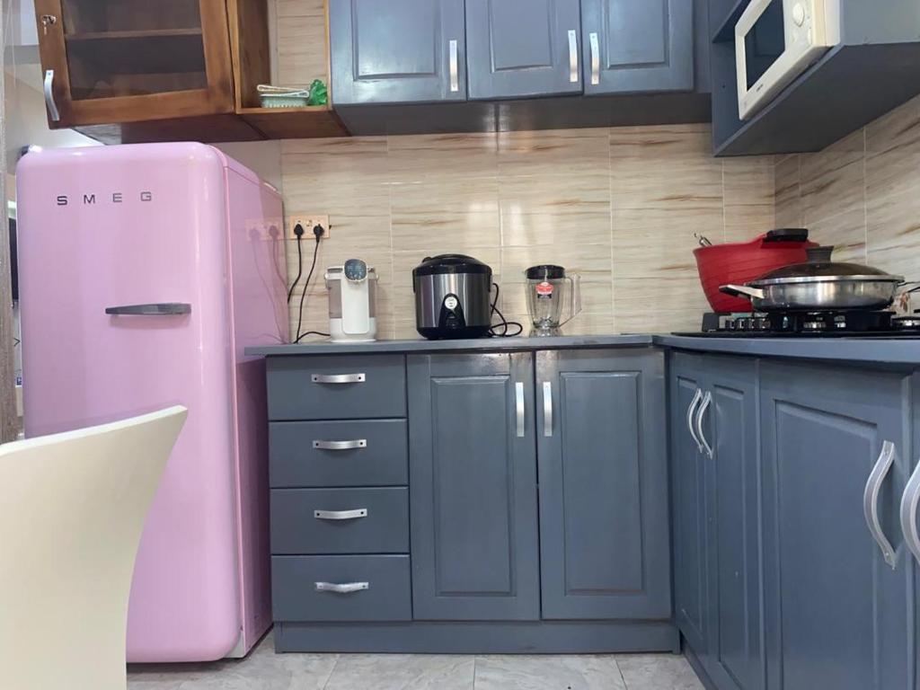 Una cocina con gabinetes azules y un refrigerador rosa. en Chic Haven cabin, en Trofwi