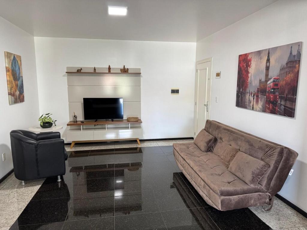 a living room with a couch and a flat screen tv at Hospedaria Sewald in Treze Tílias
