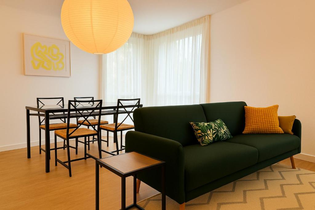 un salon avec un canapé vert et une table dans l'établissement T2 lumineux cosy avec terrasse - parking privée & métro Borderouge 5 min - proche centre ville, à Toulouse