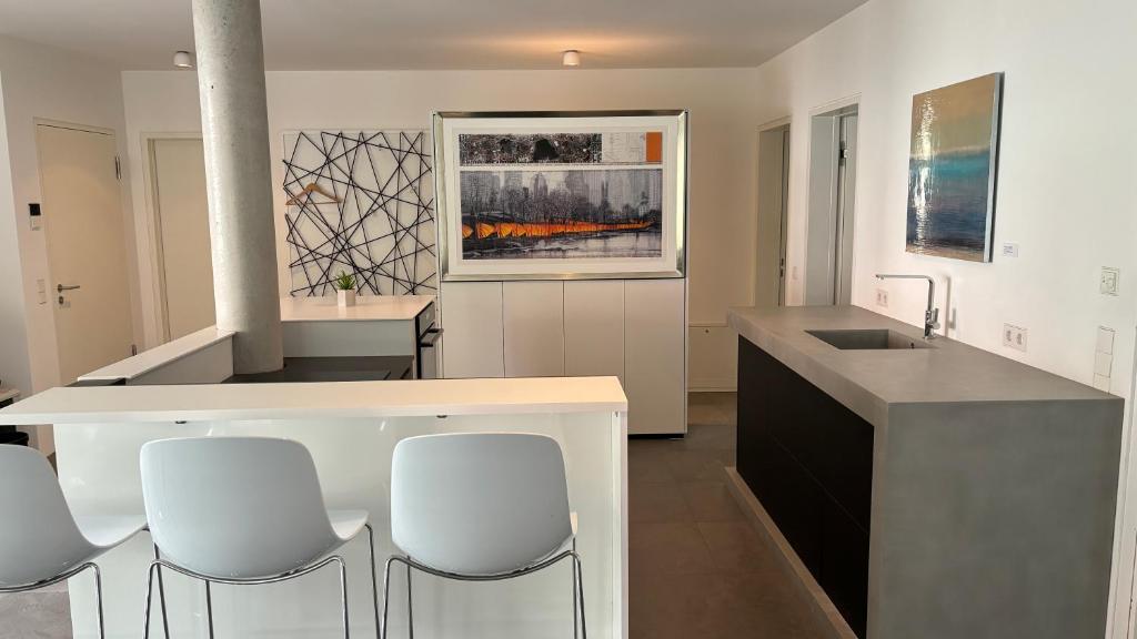 a kitchen with white chairs and a counter top at LAKE Loft Flow in Überlingen