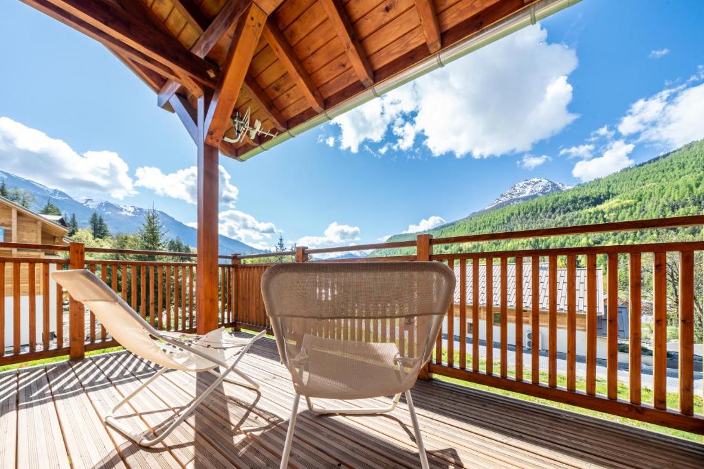 d'une terrasse avec des chaises et une vue sur les montagnes. dans l'établissement Serre Chevalier magnifique chalet, à La Salle Les Alpes