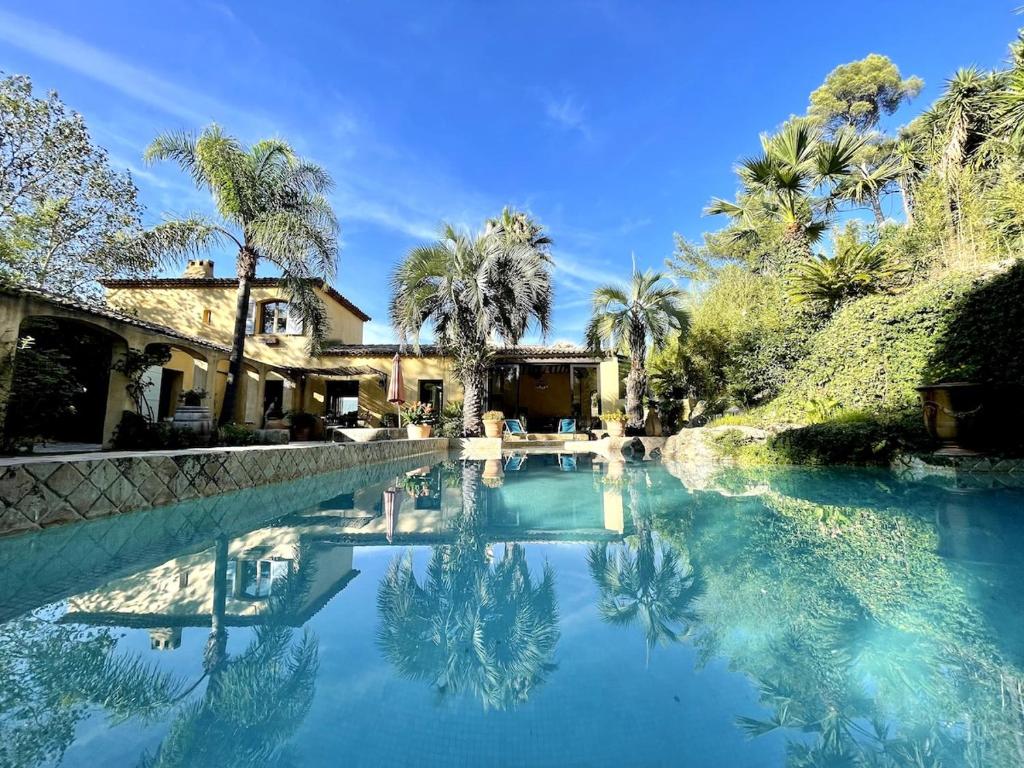 une piscine devant une maison avec des palmiers dans l'établissement Mas Saint Anne, à Évenos