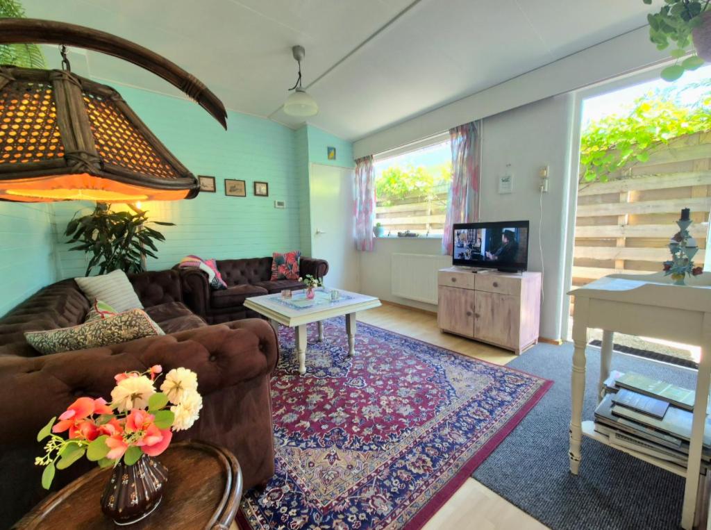ein Wohnzimmer mit Sofa und Fernseher in der Unterkunft Bungalow Texel near beach and city centre in De Koog