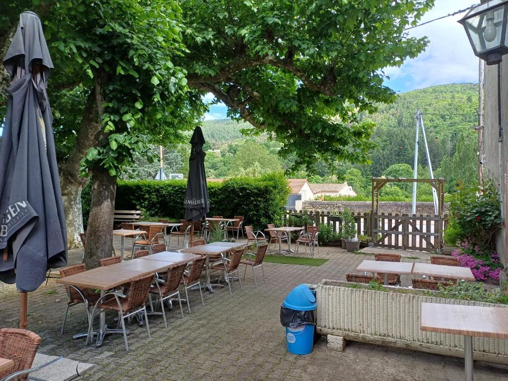 un patio extérieur avec tables, chaises et parasols dans l'établissement Auberge des Platanes, à Villevocance