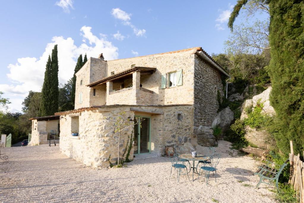 une maison en pierre avec une table et des chaises devant elle dans l'établissement La lussanaise, à Lussan