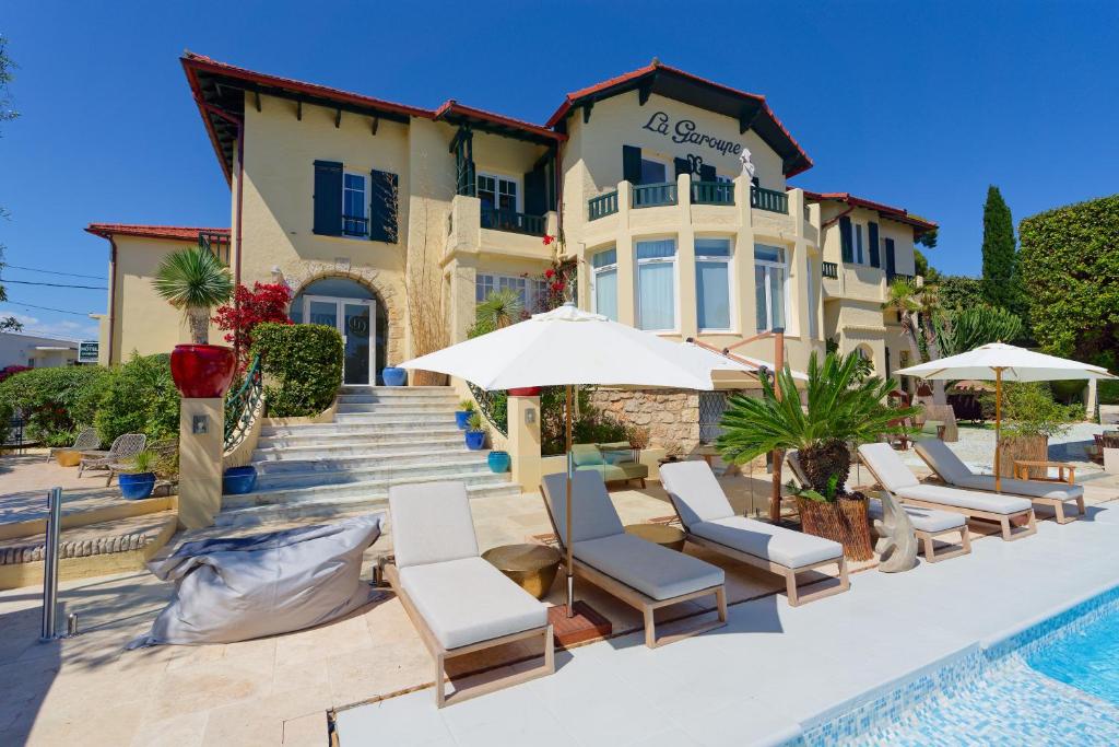 a villa with a swimming pool with chairs and umbrellas at La Garoupe-Gardiole in Antibes