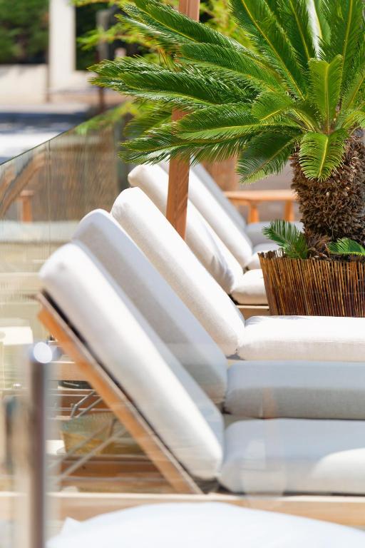 a row of white lounge chairs with a palm tree on top at La Garoupe-Gardiole in Antibes