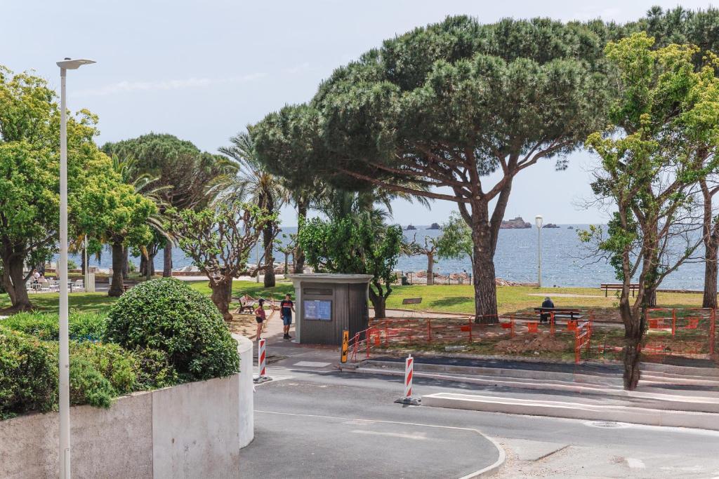 un parc avec des arbres et des gens marchant dans une rue dans l'établissement Le Neptune YourHostHelper, à Saint-Raphaël