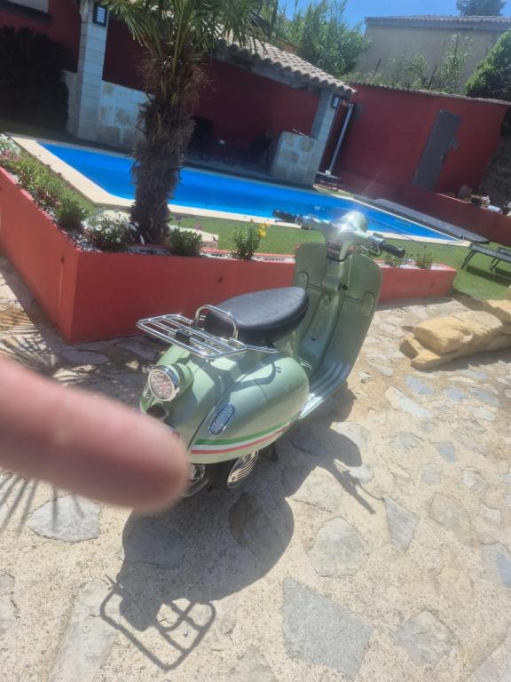 un scooter vert garé à côté d'une piscine dans l'établissement Havre de paix, à Calvisson